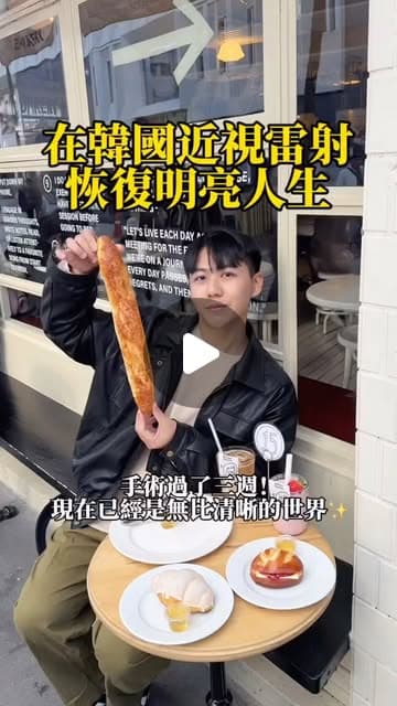 穿黑色皮夾克的邵軒坐在首爾咖啡廳戶外座位，舉著一根長法國麵包，桌上有麵包和飲料，字幕寫著「在韓國近視雷射 恢復明亮人生」「手術過了三週」